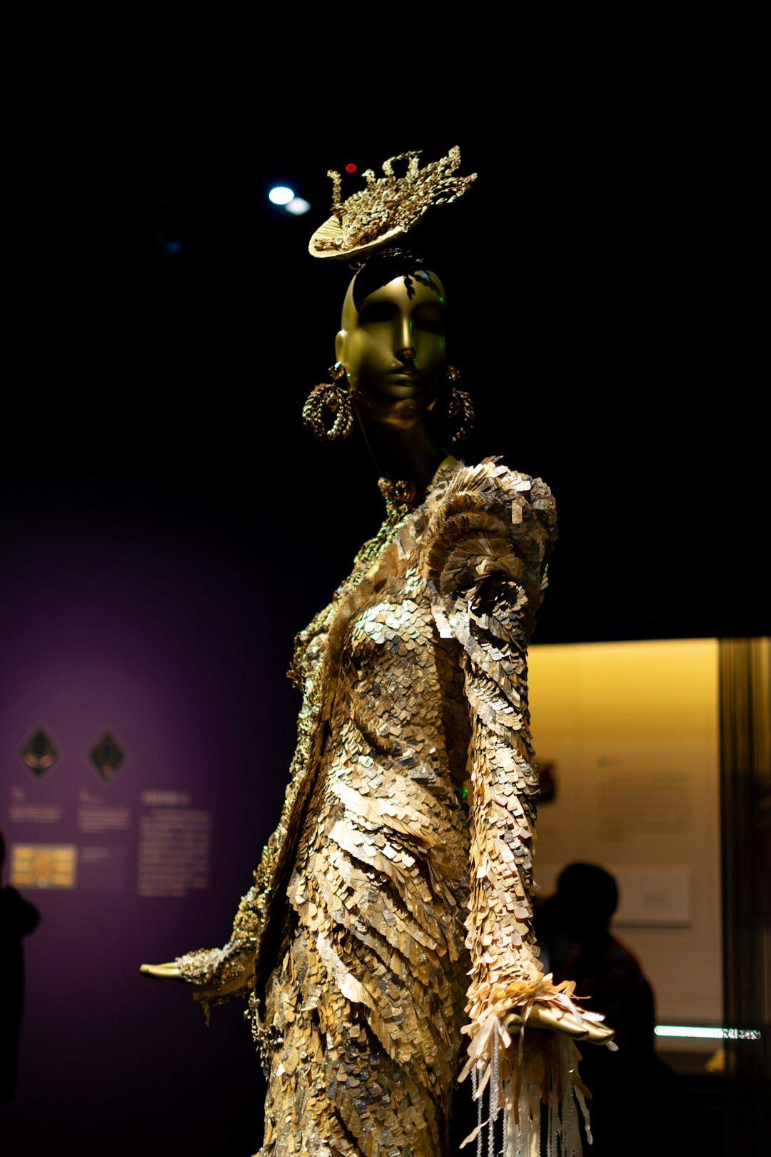 A golden mannequin in an ornate dress and textured dress.