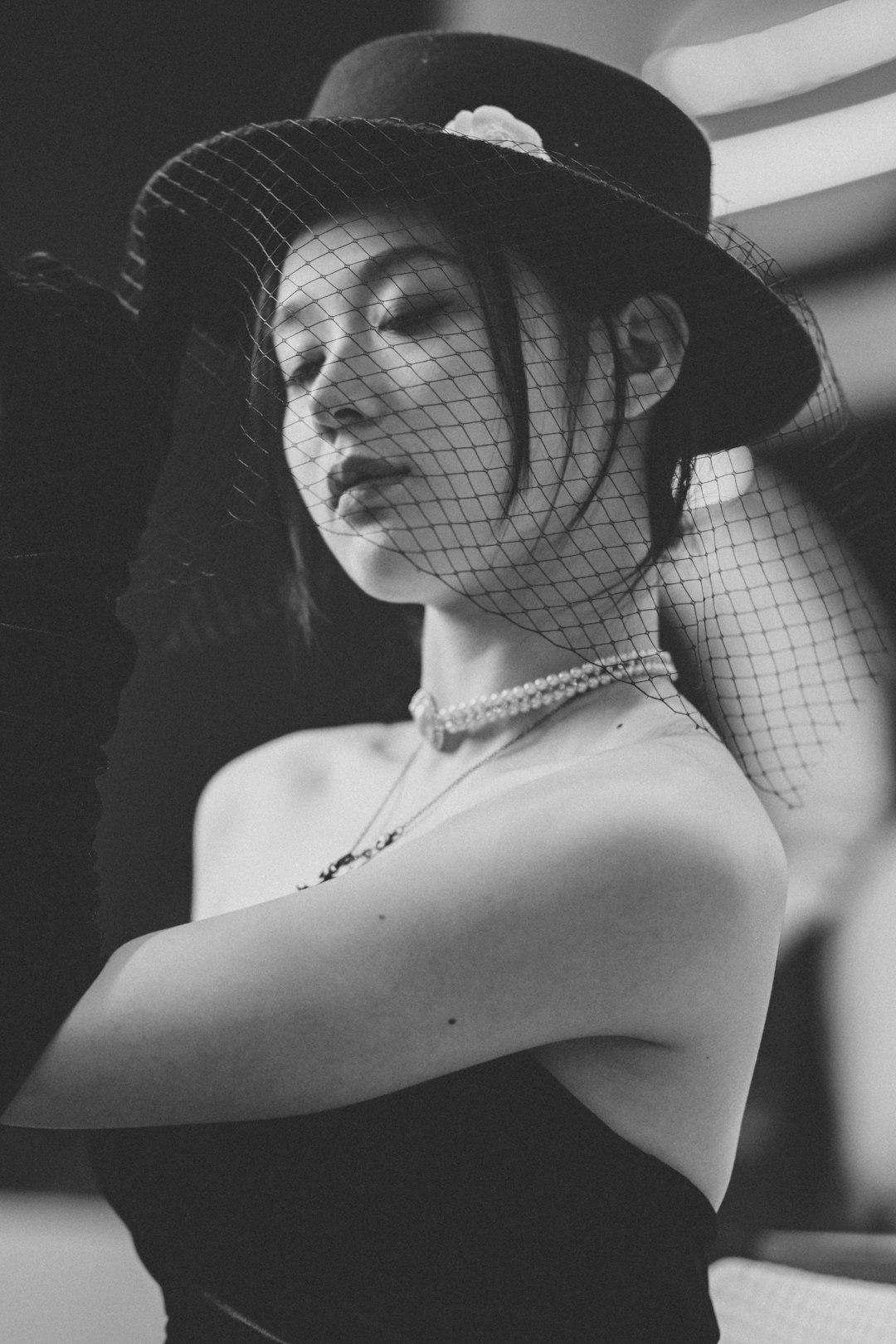 Elegant woman in a veiled hat and pearls.